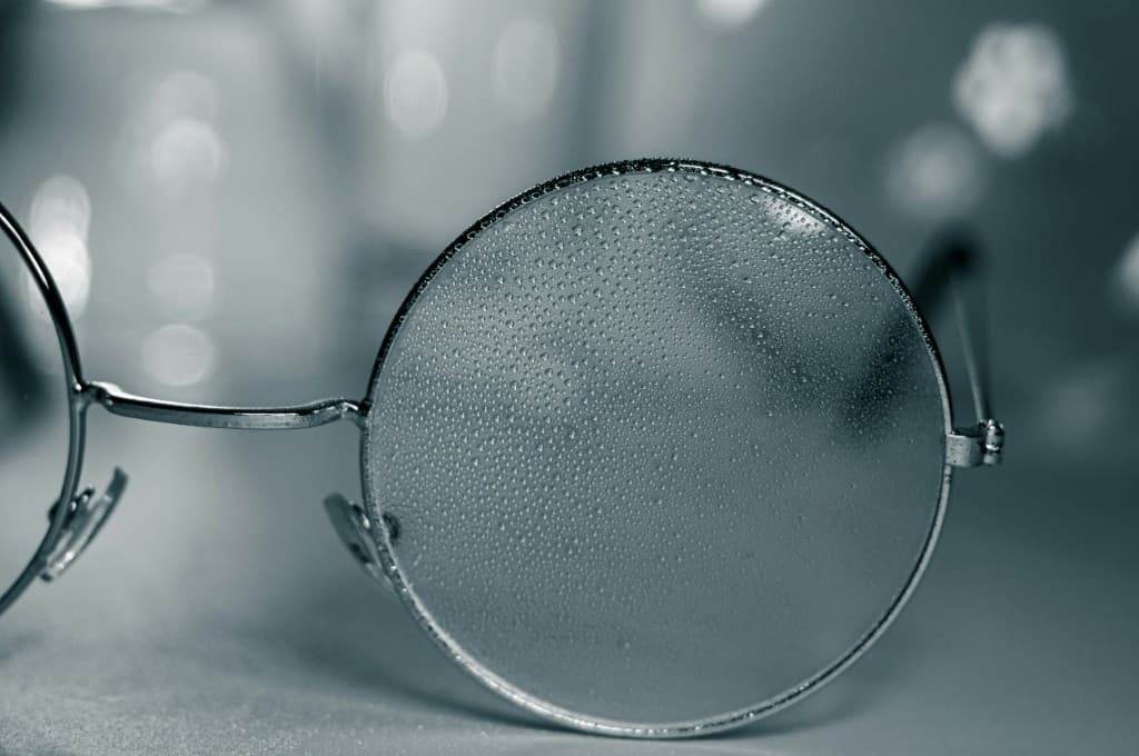 Close-up of eyeglass lenses covered in condensation, showing moisture buildup that can affect clarity without anti-fog or hydrophobic coatings.