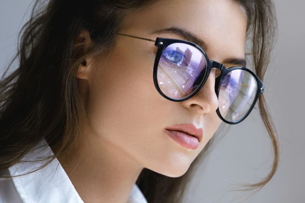 Woman wearing glasses with an anti-reflective coating that reduces glare and reflections, allowing her eyes to remain visible and clear under bright indoor lighting.