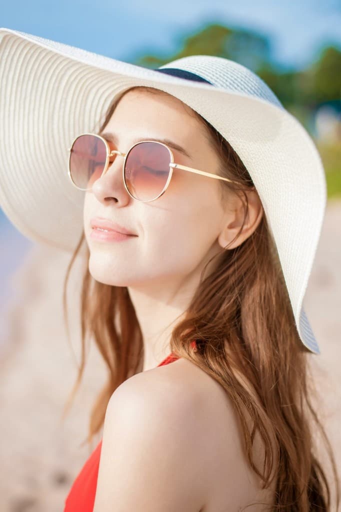 Person wearing a wide-brimmed hat and sunglasses outdoors in bright daylight, showing eye protection from sun exposure.