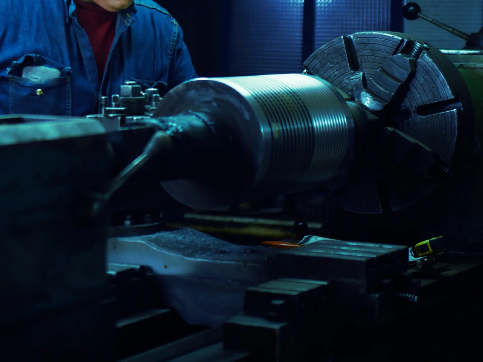 A lathe turning a steel workpiece, with swarf collected on the machine bed