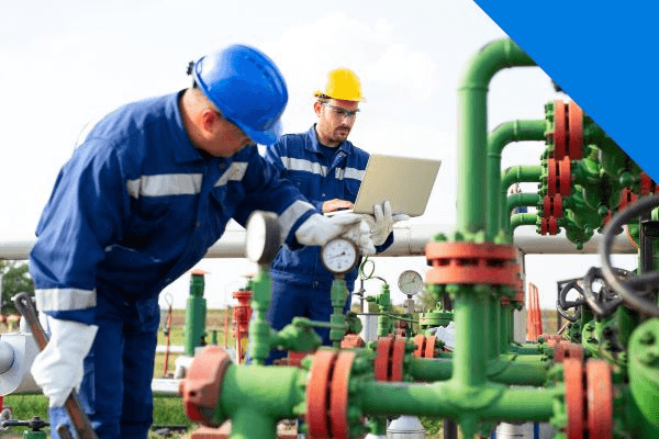 Oil and gas workers in PPE and safety eyewear inspecting pipeline equipment on site