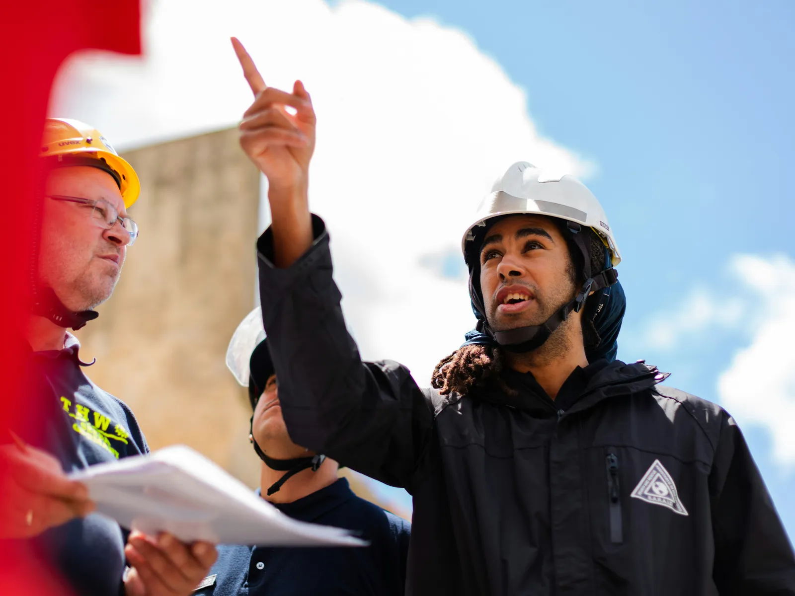 Safety team in hard hats reviewing plans on a worksite