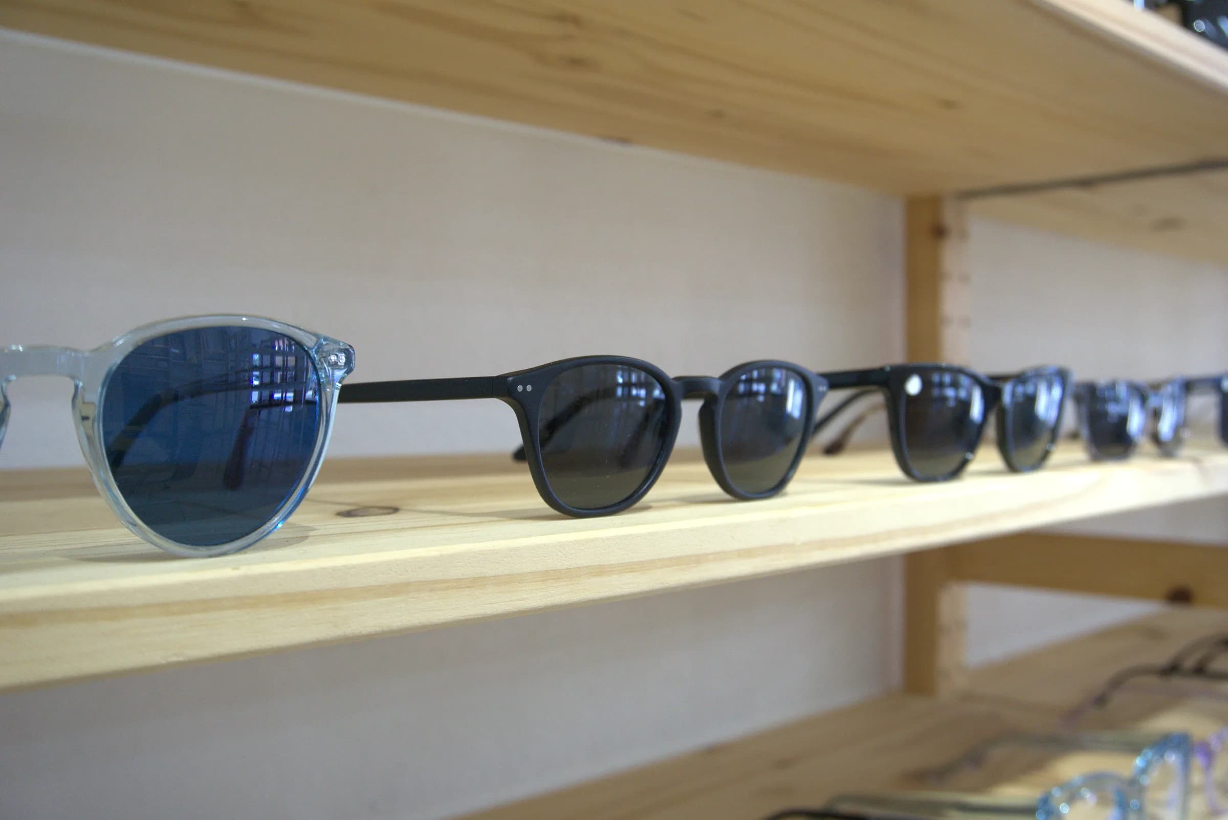 Sunglasses lined up along a wooden display shelf in the showroom
